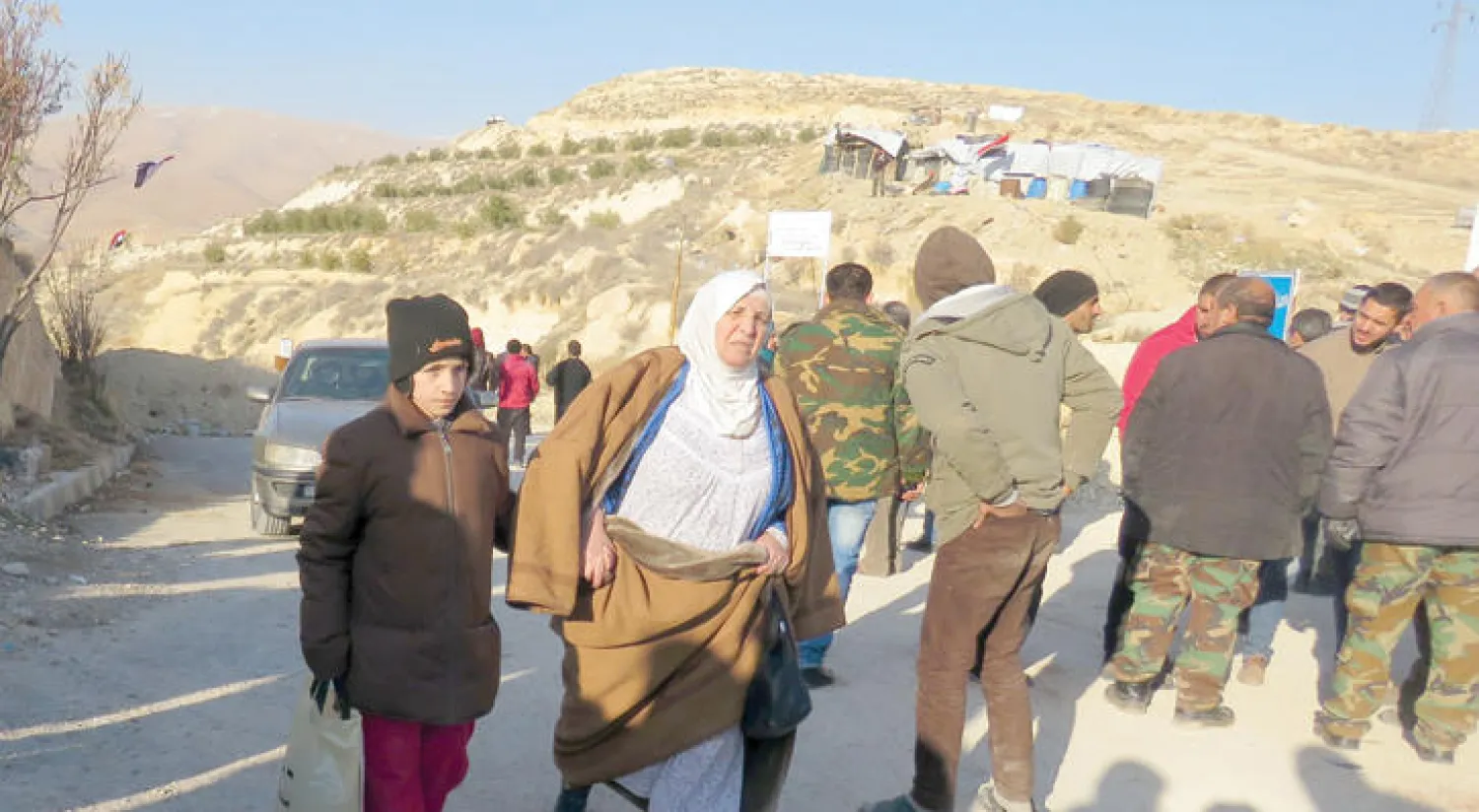 صبي مع جدته قرب حاجز تفتيش لقوات الأسد في دير قانون بوادي بردى أمس حيث يحاول بعض المدنيين الهرب من القصف (أ.ف.ب)