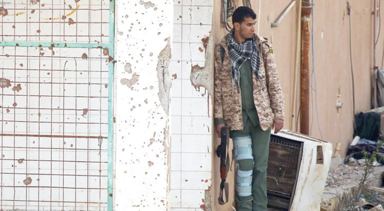 أحد عناصر الجيش الوطني الليبي محتميا بحائط خلال اشتباكات مع مجموعات إرهابية في قنفودة جنوب بنغازي (أ.ف.ب)