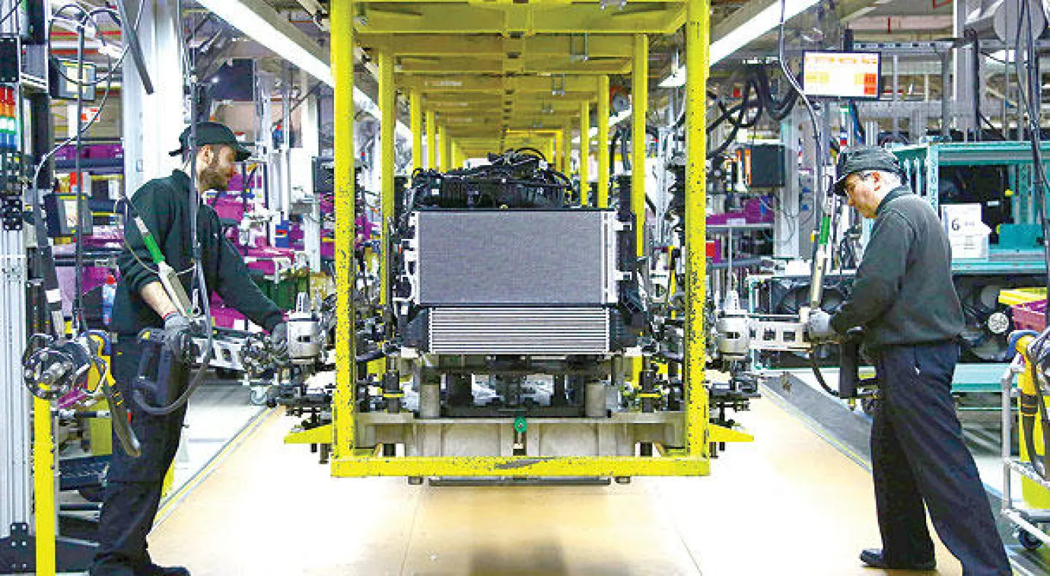 عاملان في مصنع لسيارات {بي إم دبليو} بمدينة أكسفورد البريطانية (أ.ف.ب)