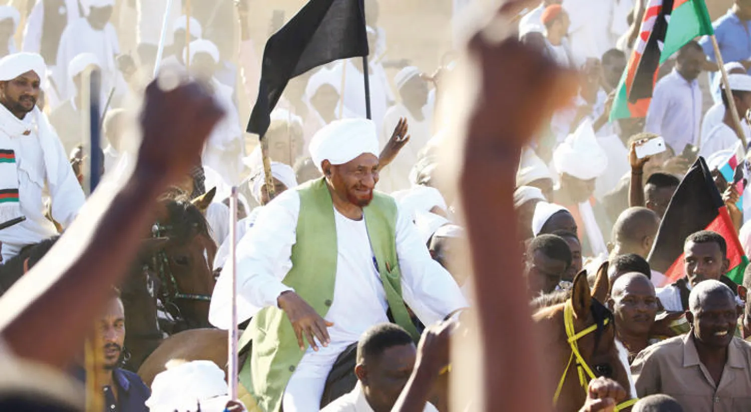 الصادق المهدي على صهوة جواد وسط أنصاره لدى عودته إلى الخرطوم أمس (أ.ف.ب)