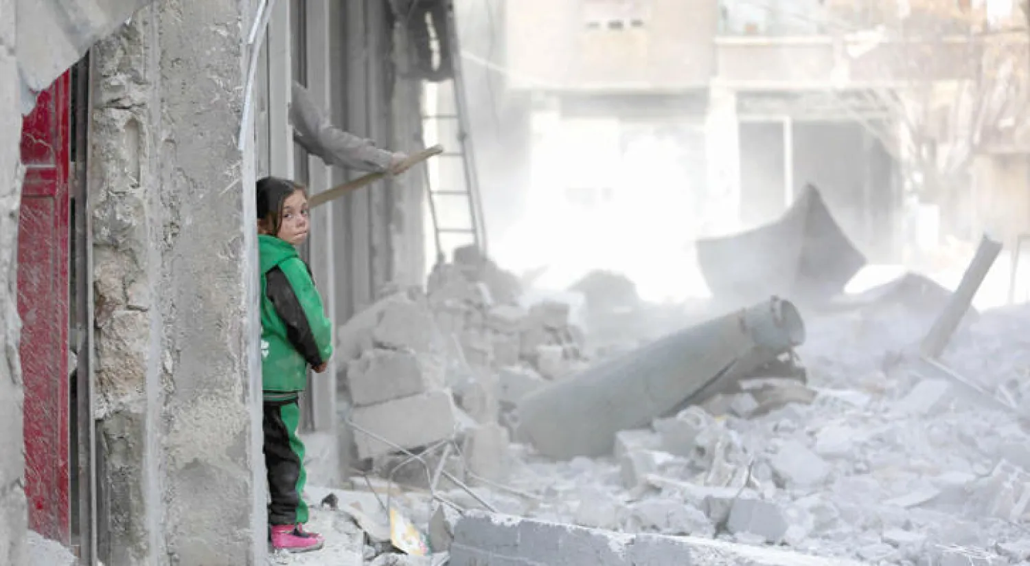 طفلة سورية تطل على الدمار الذي سببته غارات النظام على منزل عائلتها في عربين بالغوطة الشرقية (أ.ف.ب)