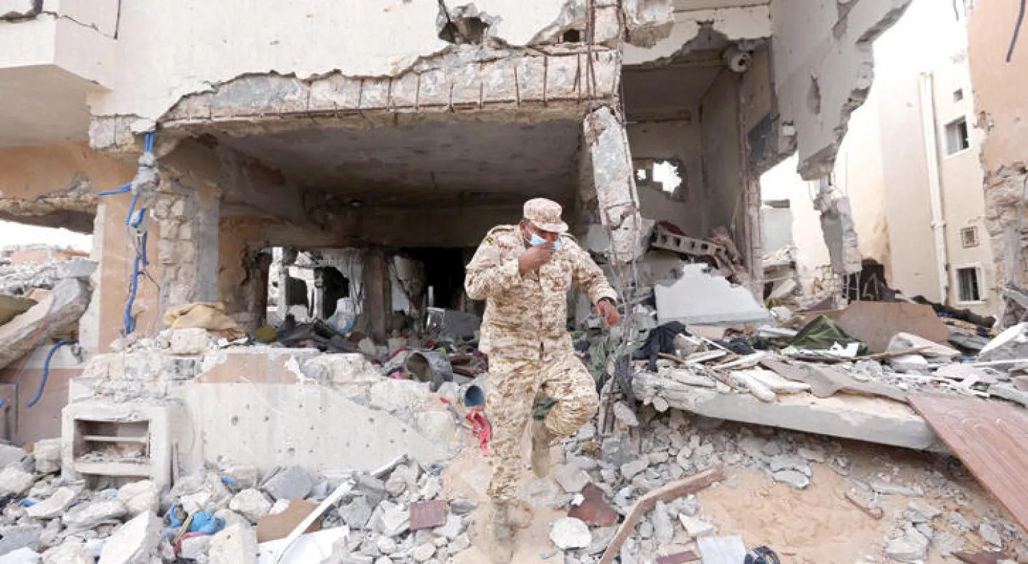 عنصر من الأمن الليبي يعاين آثار بناية دمرت بالكامل خلال معارك ضد تنظيم «داعش» في مدينة سرت (أ.ف.ب)
