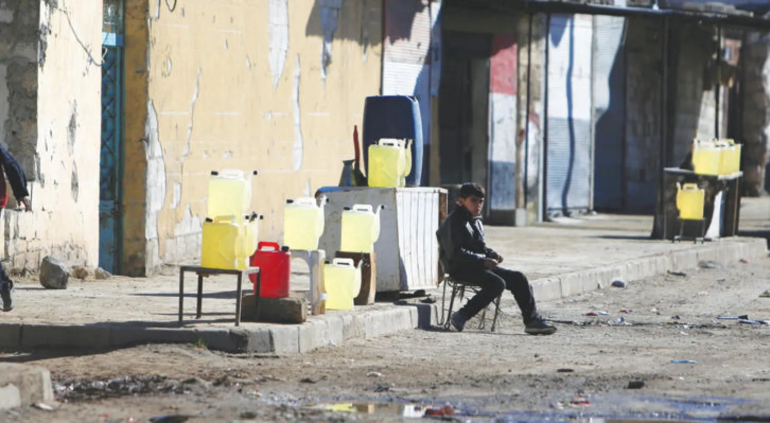 طفل سوري يبيع وقودًا في شارع بمدينة حلب أمس (رويترز)