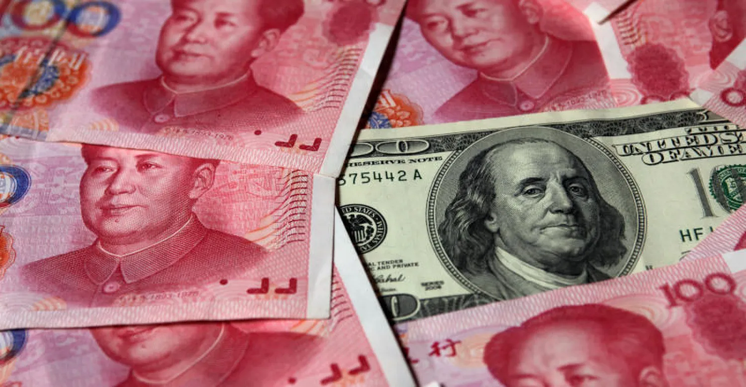عملات فئة 100 دولار أميركي و100 يوان صيني في بكين (رويترز)