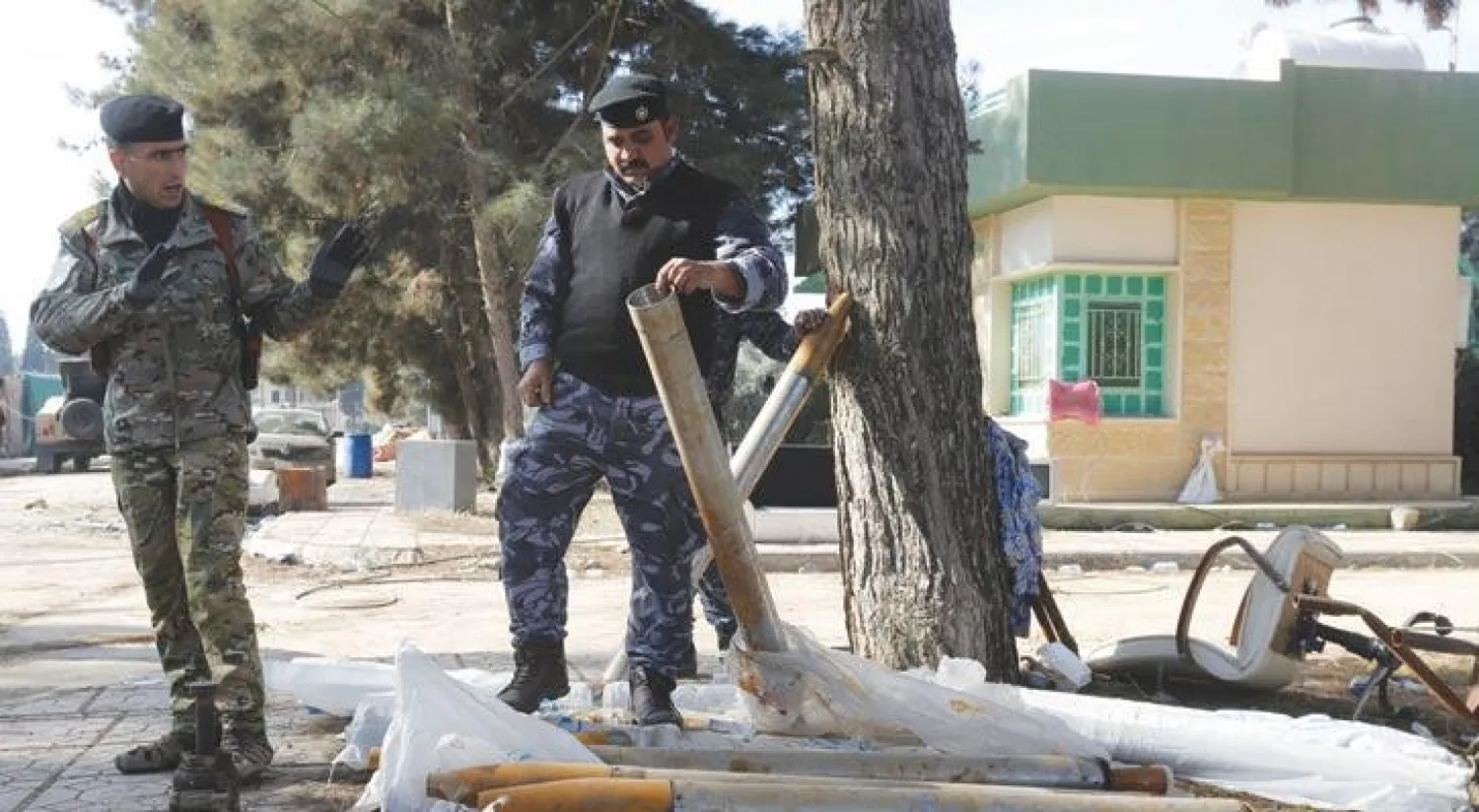 عنصرا أمن عراقيان يعاينان صواريخ تركها تنظيم داعش وراءه في شرق الموصل (رويترز)