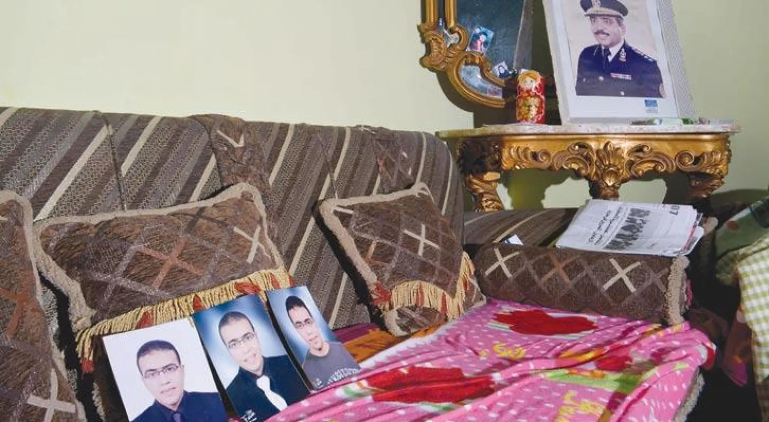 صور لمنفذ الهجوم عبد الله رضا الحماحمي، 29 عامًا، في منزل العائلة بمدينة المنصورة  بمحافظة الدقهلية مع صورة في الخلف لوالده اللواء شرطة متقاعد علقت على جدران الغرفة (أ.ف.ب)