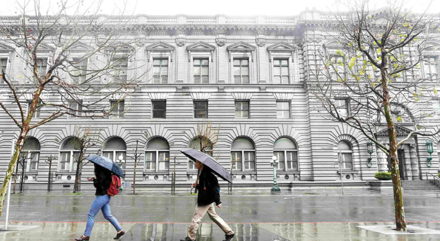 شخصان يمران أمام مبنى المحكمة الفيدرالية في سان فرانسيسكو التي بدأت أمس النظر في استئناف الحكومة ضد قرار تعليق حظر السفر (رويترز)