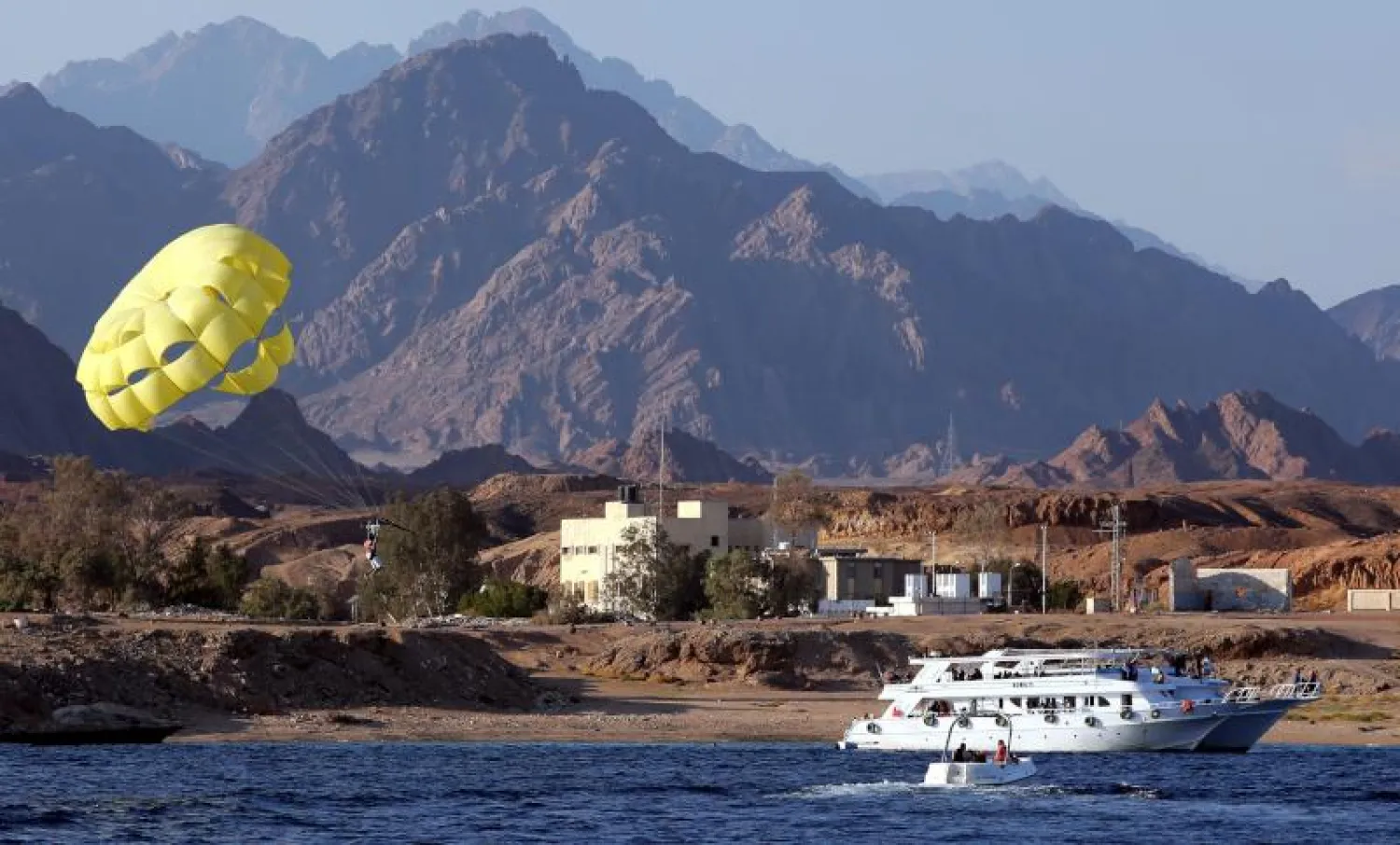 سائحون يستمتعون بركوب المظلات فوق مياه البحر الأحمر بمدينة شرم الشيخ المصرية (إ.ب.أ)