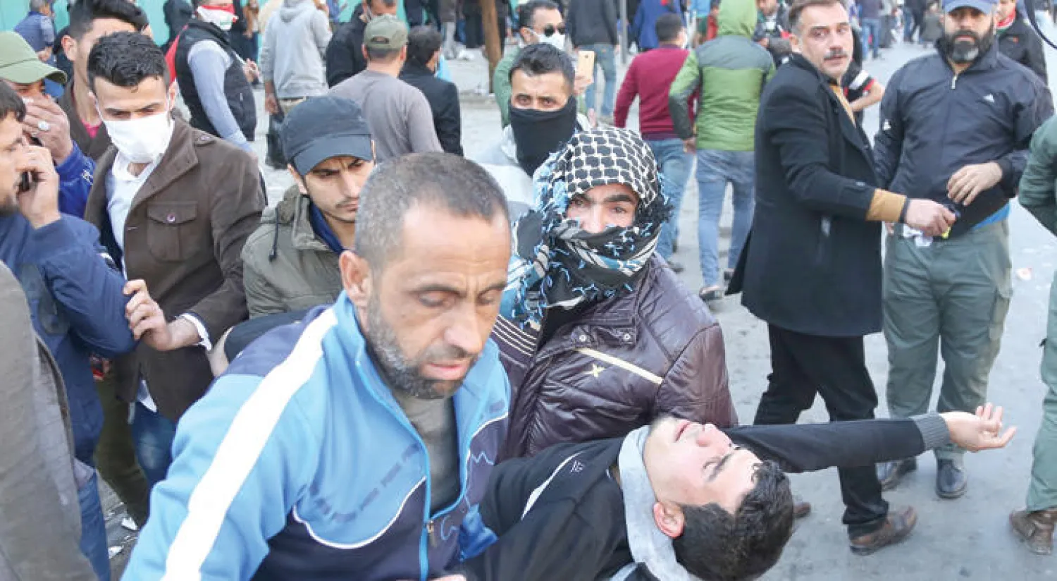 متظاهرون يحملون أحد رفاقهم الذي أصيب خلال المواجهات مع قوات الأمن في ساحة التحرير ببغداد أمس (أ.ب)