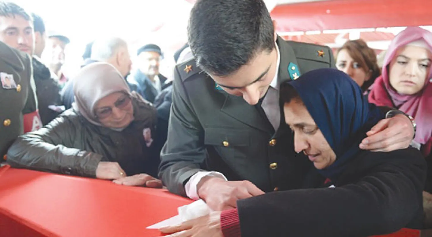 أم ملازم تركي قتل في عملية درع الفرات في سوريا وشقيقه الذي يرتدي بزة أخيه العسكرية يودعان جثمانه خلال مراسم تشييعه في منطقة غوريل بتركيا أمس (غيتي)