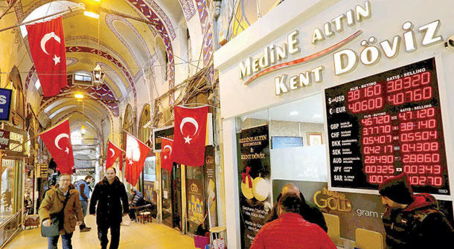 السوق الكبير في اسطنبول ويبدو إلى جانبه لوحة تظهر أسعار العملات مقابل الليرة التركية (رويترز)