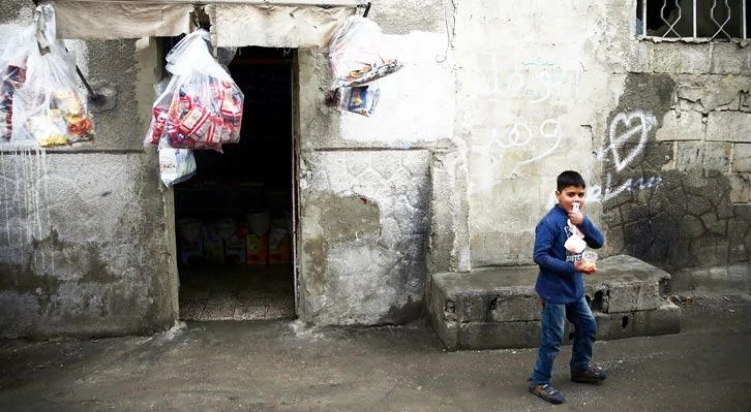 طفل يخرج من محل بقالة في دوما المحاصرة بالغوطة الشرقية لدمشق (رويترز)