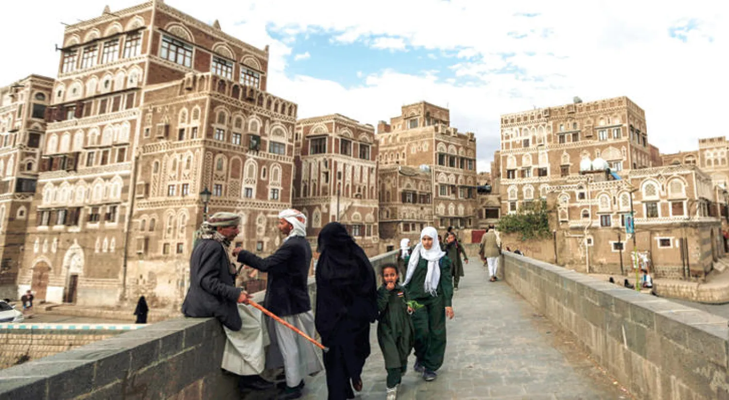 يمنيون يعبرون جسرًا مطلاً على المدينة القديمة في صنعاء أمس (أ.ف.ب)