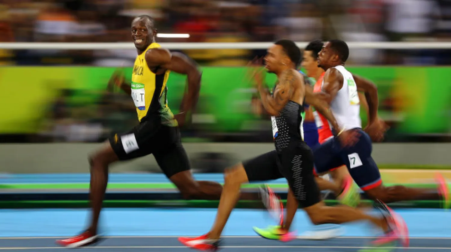 الجامايكي بولت يبتسم بينما ينظر إلى منافسيه خلال فوزه بسباق نصف النهائي 100 م عدو بأولمبياد ريو دي جانيرو 2016 (رويترز)