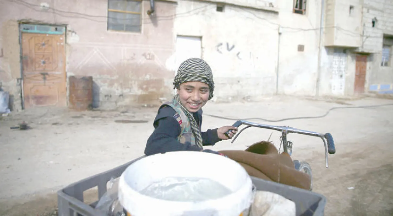 صبي من دوما المحاصرة بريف دمشق، ينقل الماء على دراجته (رويترز)