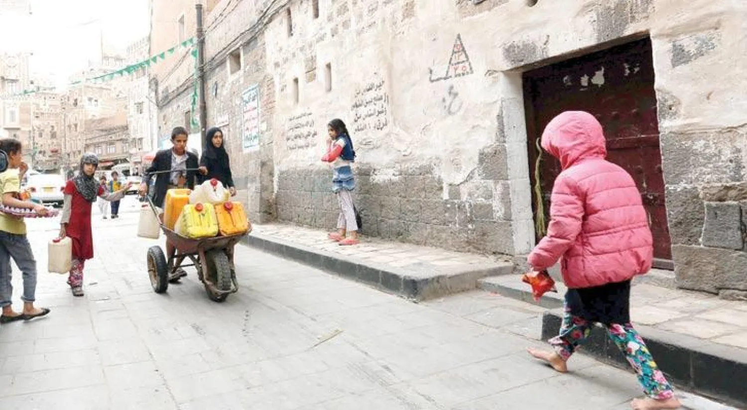 أطفال يمنيون ينقلون الماء في المدينة القديمة بصنعاء أمس (إ.ب.أ)