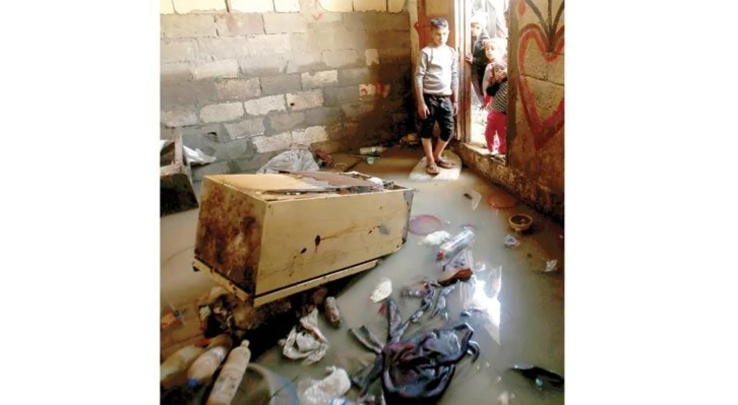 أطفال في غزة يعاينون منزلهم الذي غمرته مياه الأمطار (رويترز)