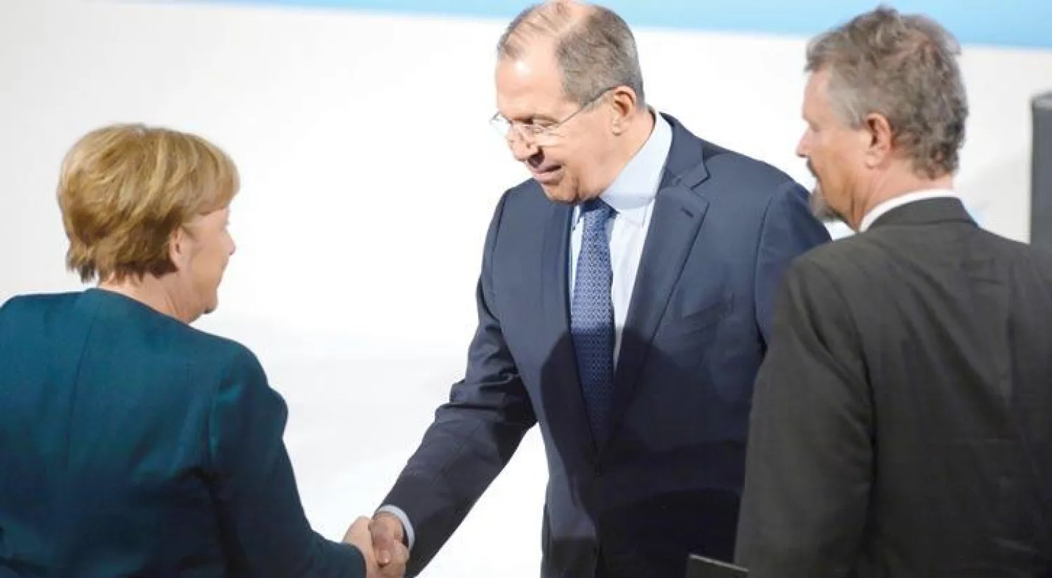 المستشارة الألمانية أنجيلا ميركل تصافح وزير الخارجية الروسي سيرغي لافروف خلال قمة ميونيخ للأمن أمس (أ.ف.ب)