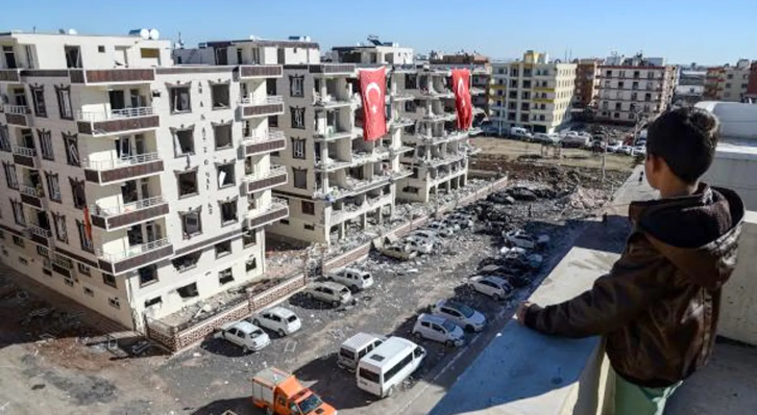 طفل يشاهد المجمع السكني في بلدة فيران شهير الذي استهدف بتفجير إرهابي أمس (أ.ف.ب)