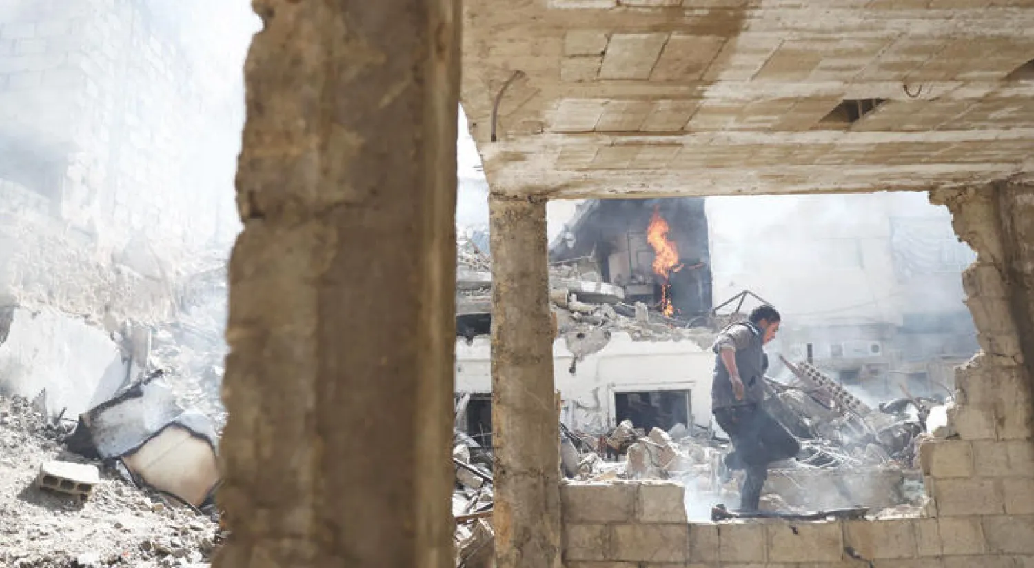 شاب من سكان دوما بالغوطة الشرقية لدمشق، يعبر ركام بناء دمره قصف طيران النظام (أ.ف.ب)