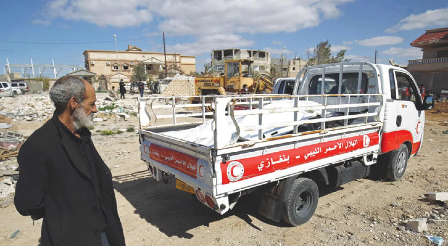 ليبي ينظر إلى سيارة نقل تابعة لمنظمة الهلال الأحمر الليبي وهي تحمل جثمان شخص عثر عليه في قبر جماعي (أ.ف.ب)