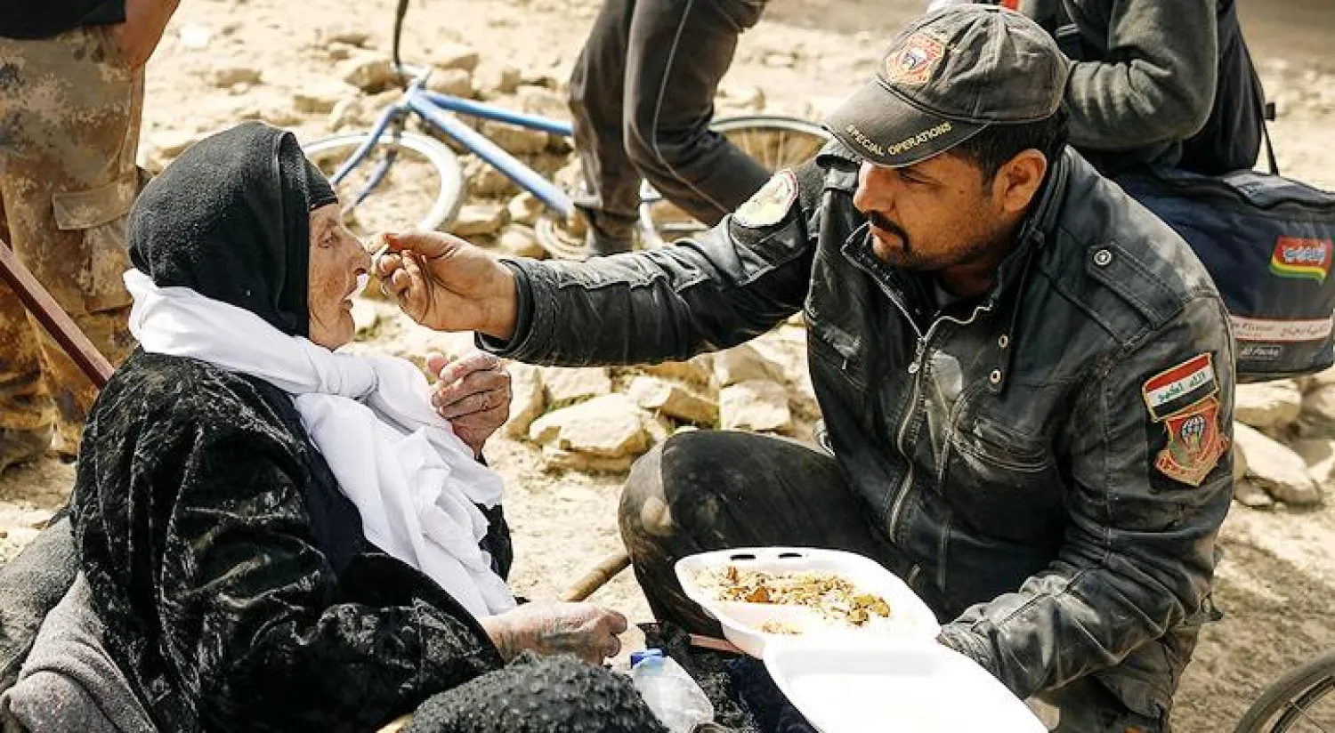 جندي من القوات الخاصة العراقية يقوم باطعام  نازحة مسنة (رويترز)