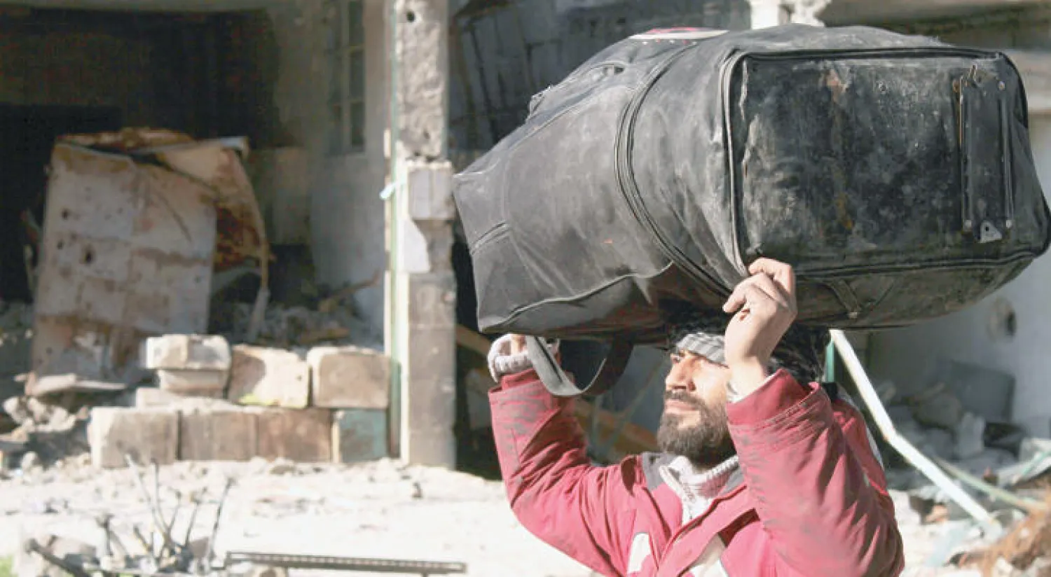 رجل من حلب يحمل أمتعته في كيس خلال إخلاء قسري للمدنيين والمسلحين من شرق المدينة المحاصرة
