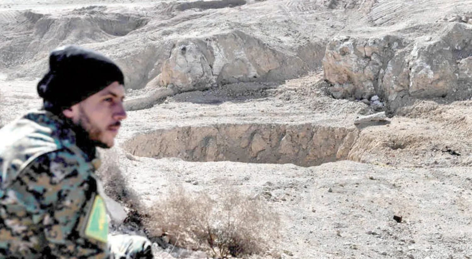 جندي عراقي يجلس بالقرب من حفرة «الخسفة» خارج الموصل (واشنطن بوست)