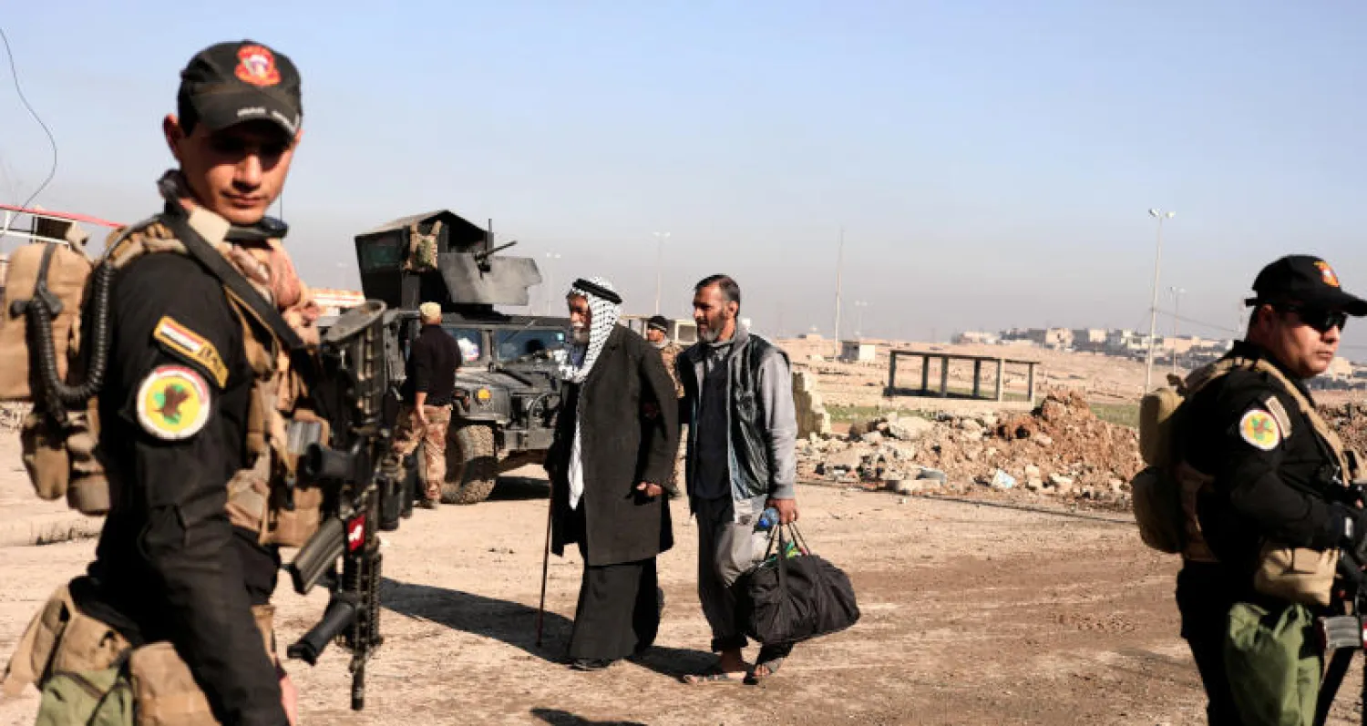 نازحون عراقيون يمرون من أمام أفراد القوات الخاصة بالموصل (رويترز)