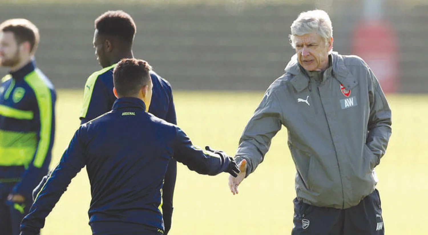 فينغر يصافح سانشيز خلال تدريبات أمس مؤكدا عدم وجود مشكلات (رويترز)