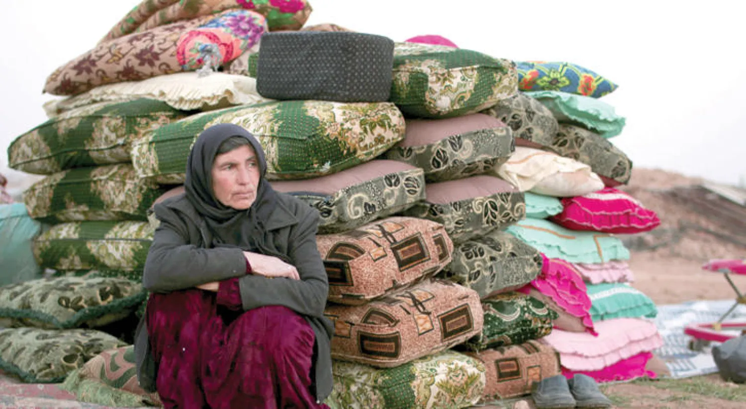 نازحة سورية في مدينة منبج أمس تستند إلى أمتعة بعد أن غادرت مع عائلتها هربا من المعارك في ريف حلب الشرقي (رويترز)