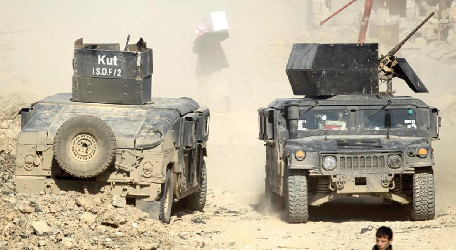 عراقي يحمل علبة مساعدات في أحد شوارع غرب الموصل أمس (رويترز)