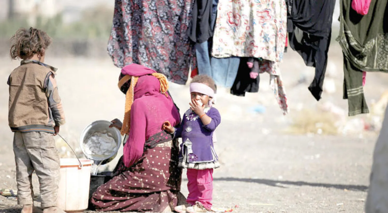 يمنية تجلس مع أطفالها بجوار مخيم للنازحين قرب صنعاء (رويترز)