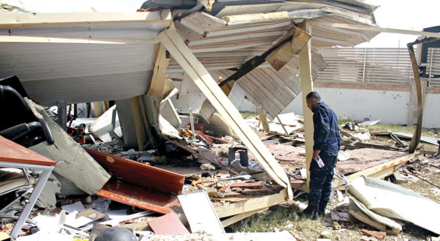 عنصر أمن ليبي يعاين الدمار الذي تعرض له أحد مقرات حكومة الغويل بعد أن سيطرت عليها قوات فائز السراج أمس (رويترز)