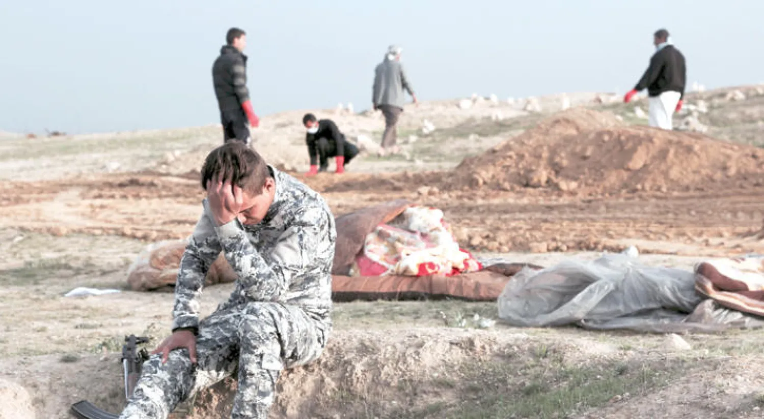 شرطي عراقي بعد العثور على مقبرة جماعية تضم جثث 20 شخصاً في منطقة محررة غرب الموصل (أ.ب)