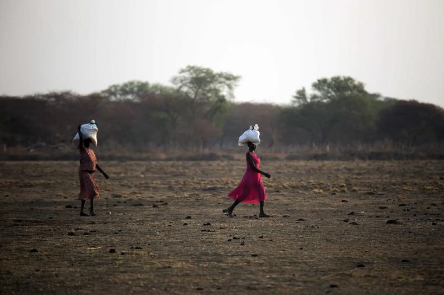 نساء يحملن أجولة الغذاء من مركز لتوزيع المساعدات الإنسانية في جنوب السودان (أ ف ب )