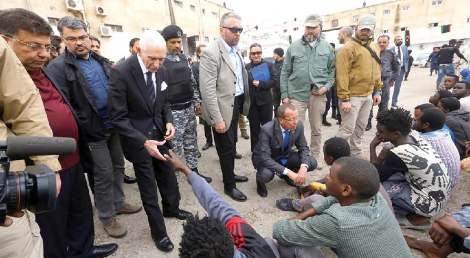 المدير العام للمنظمة العالمية للهجرة يصافح أحد اللاجئين في العاصمة الليبية طرابلس أمس (أ.ف.ب)