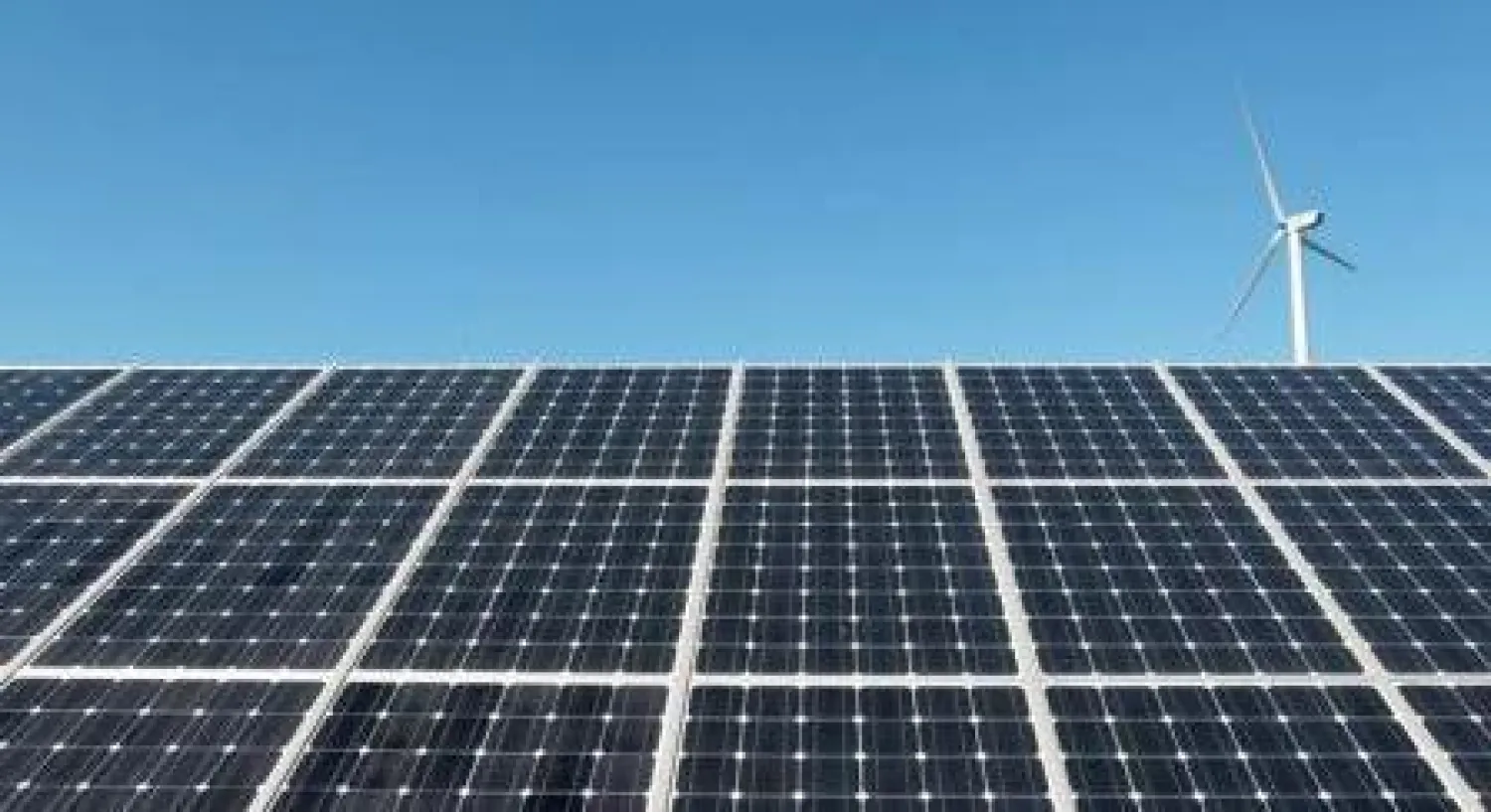 توربين لتوليد الطاقة من الرياح خلف ألواح شمسية في كوريا الجنوبية (رويترز)