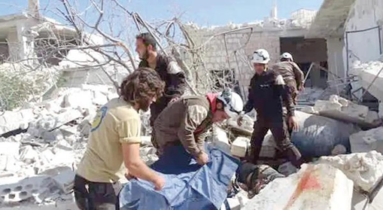 عناصر من الدفاع المدني يبحثون عن ضحايا غارات على مجمع مدارس في بلدة حاس بريف إدلب (موقع الدفاع المدني)