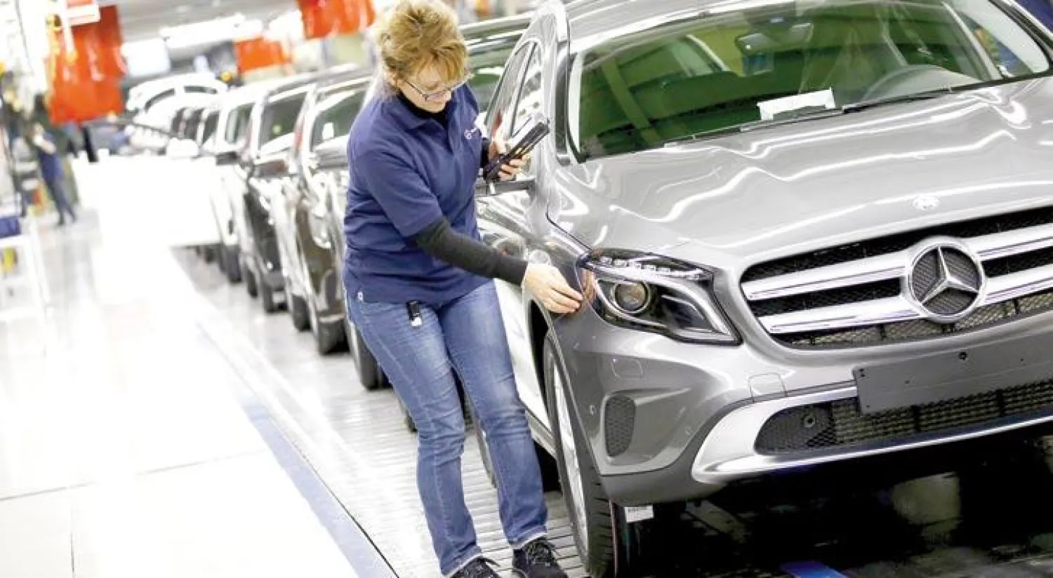 صورة أرشيفية لمهندسة ألمانية تلقي نظرة على سيارة مرسيدس في آخر مراحل إنتاجها (رويترز)