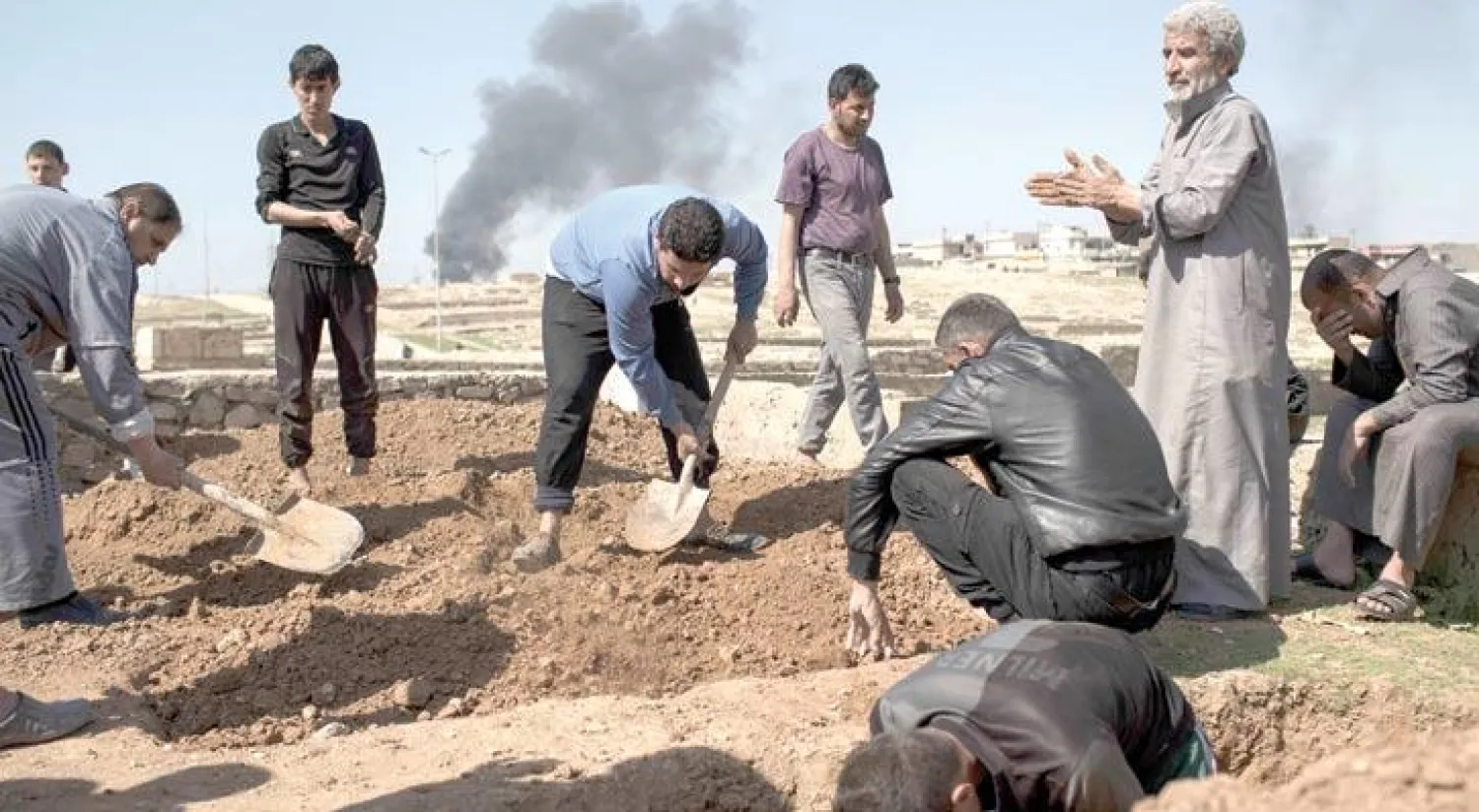 عراقيون يحفرون قبرين لمدنيين قتلا خلال المواجهات بين القوات العراقية و«داعش» في غرب الموصل أمس (أ.ب)