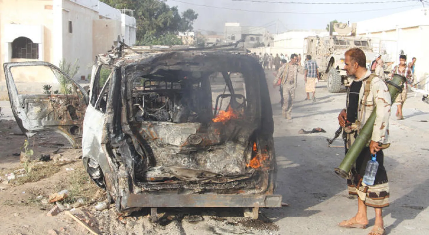 بقايا سيارة مفخخة فجرت في حوتا التابعة لمقاطعة لحج الجنوبية ويبدو بجانبها احد المسلحين (أ.ف.ب)