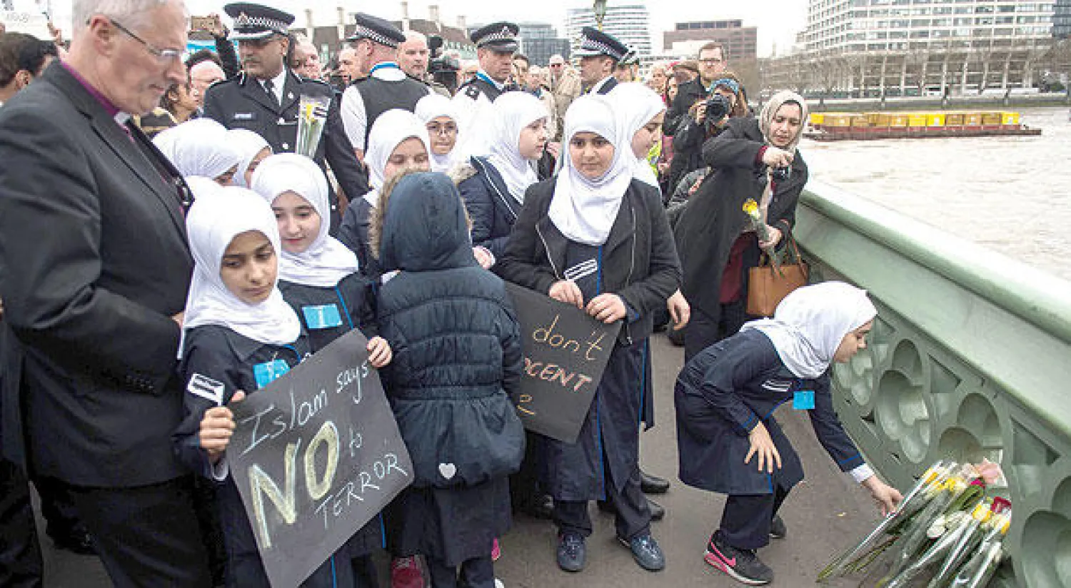 عناصر من الشرطة البريطانية وأعضاء من الجالية المسلمة في بريطانيا يقفون على جسر وستمنستر أمس لاستذكار ضحايا الهجوم (أ.ف.ب)