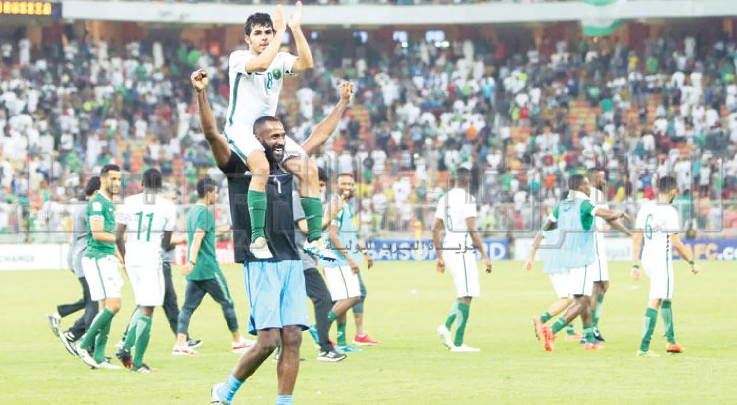 الشهري صاحب هدف الفوز السعودي على كتفي زميله الحارس وليد عبد الله (تصوير: محمد المانع)