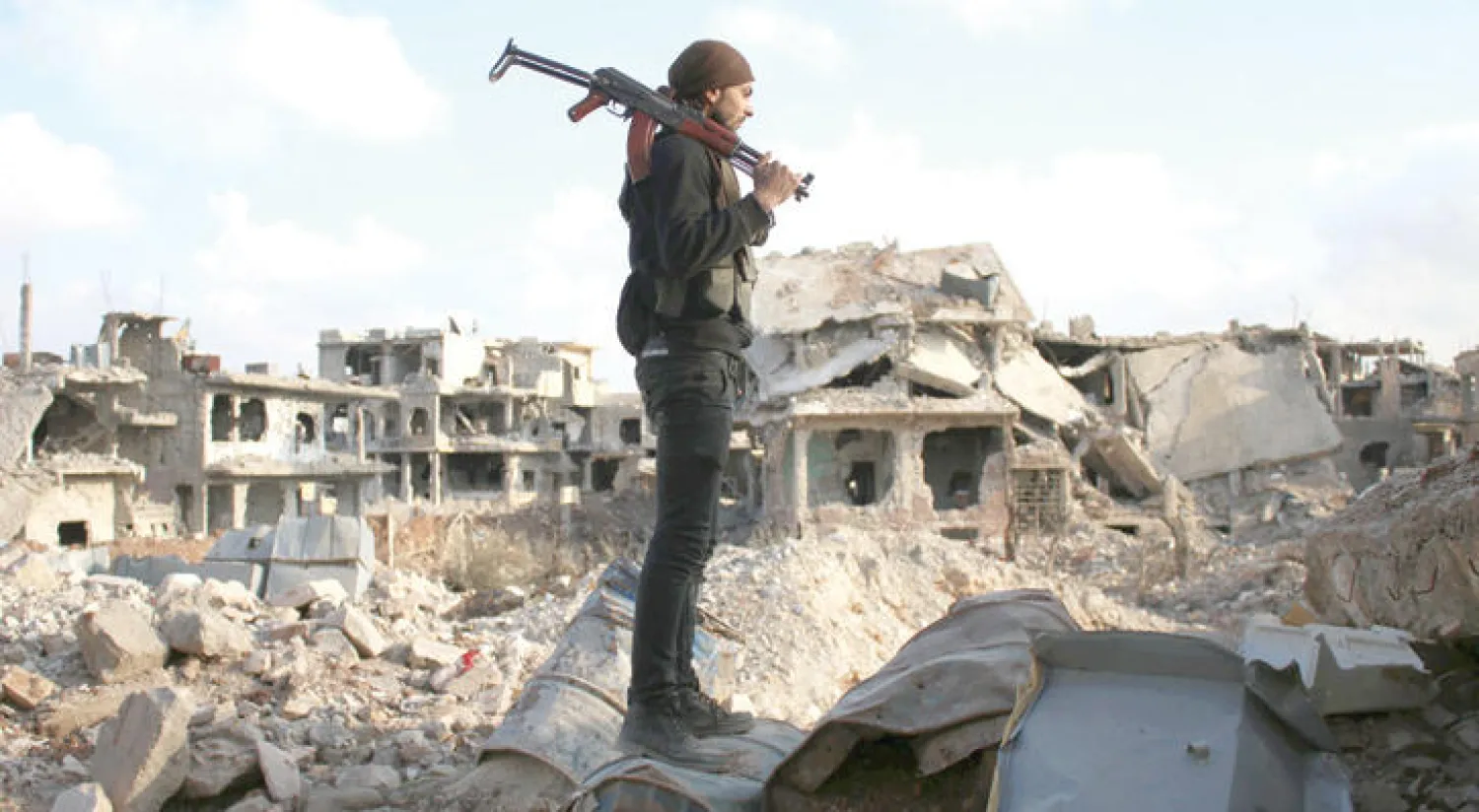 مقاتل من الفصائل المعارضة في درعا جنوب سوريا يقف وسط ركام الأبنية التي دمرها قصف الطيران الحربي المتواصل على المنطقة (أ.ف.ب)