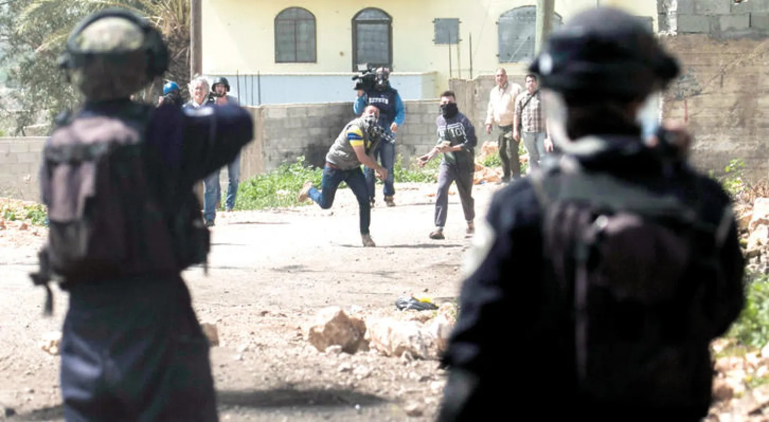 مواجهة بين جنديين إسرائيليين ومتظاهرين فلسطينيين ضد مصادرة الأراضي في الضفة أمس (أ.ف.ب)