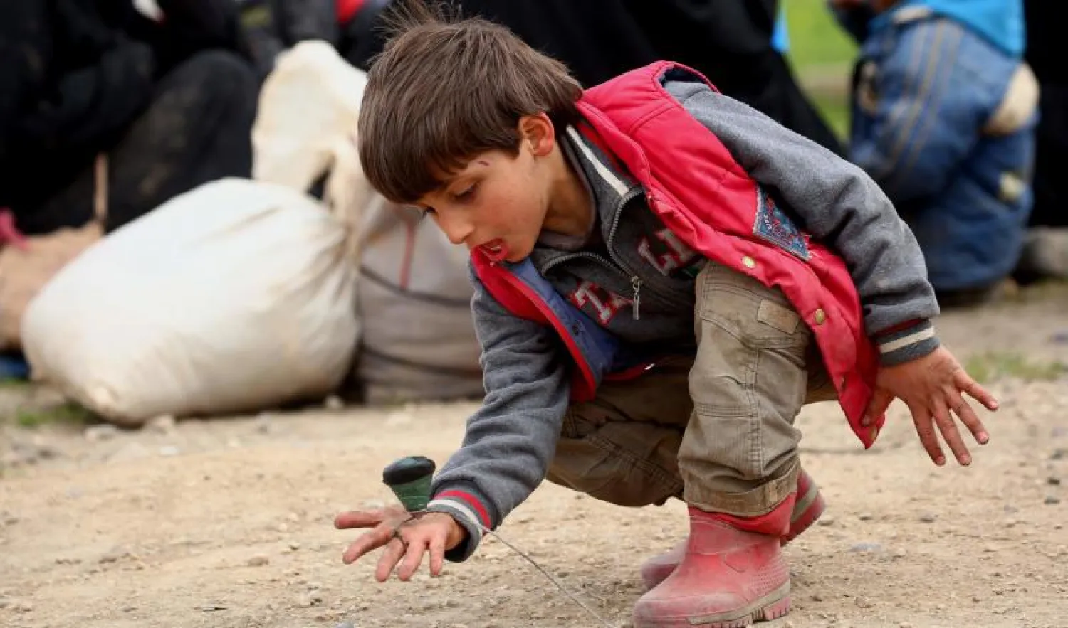 طفل سوري فر من معاقل «داعش» في الرقة يلعب عند وصوله إلى مخيم مؤقت بقرية عين عيسى (أ.ف.ب)