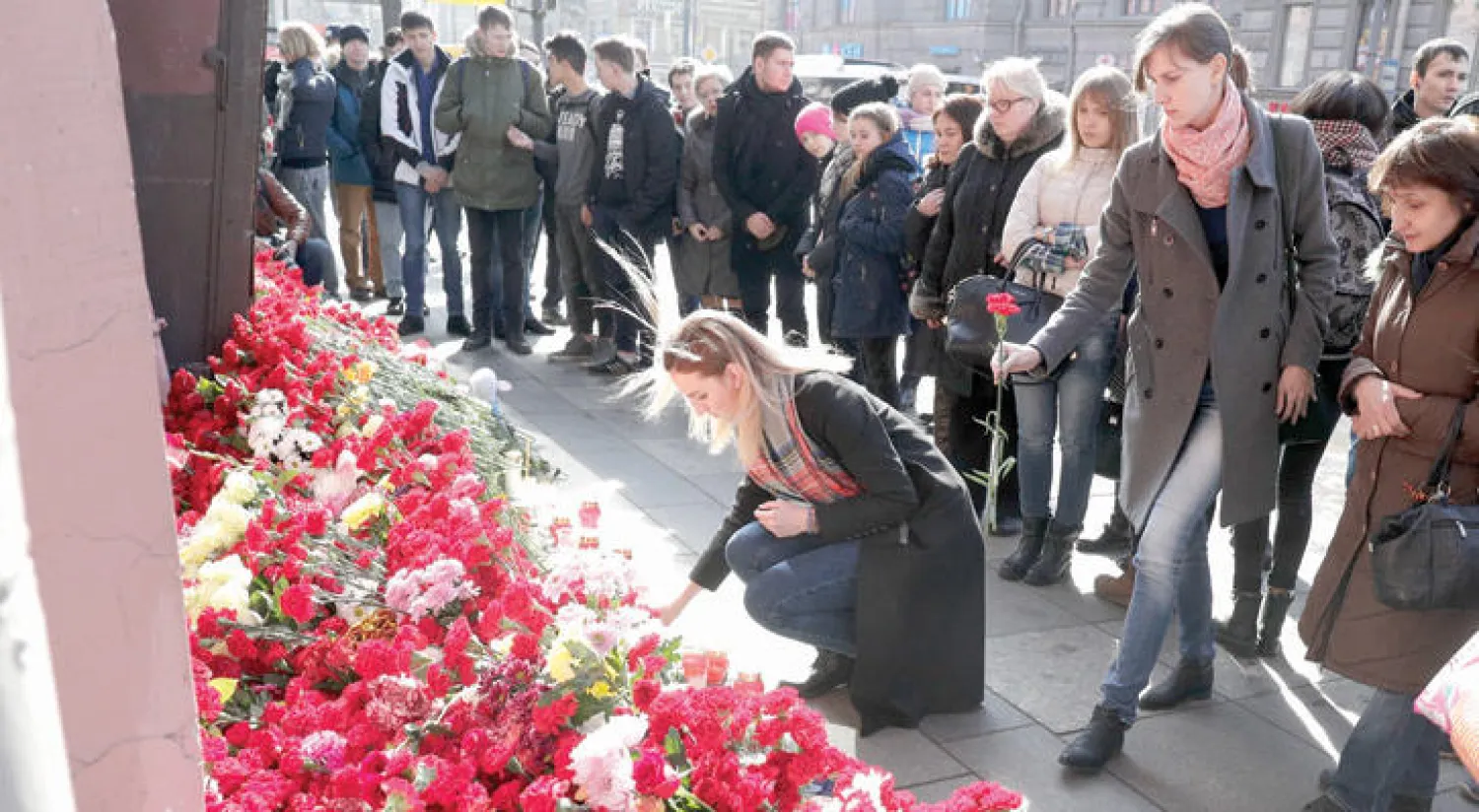 سيدة روسية تضع باقة من الورود لأرواح ضحايا التفجير الانتحاري في مواجهة محطة مترو تضامناً مع سان بطرسبرغ أمس (أ.ب)