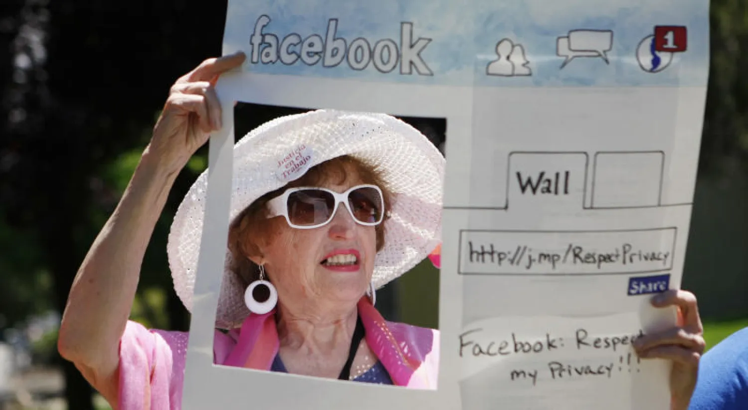 امرأة أميركية تحمل مجسماً ورقياً لصفحة «فيسبوك» كتب عليها: احترموا خصوصيتي (أ.ب)