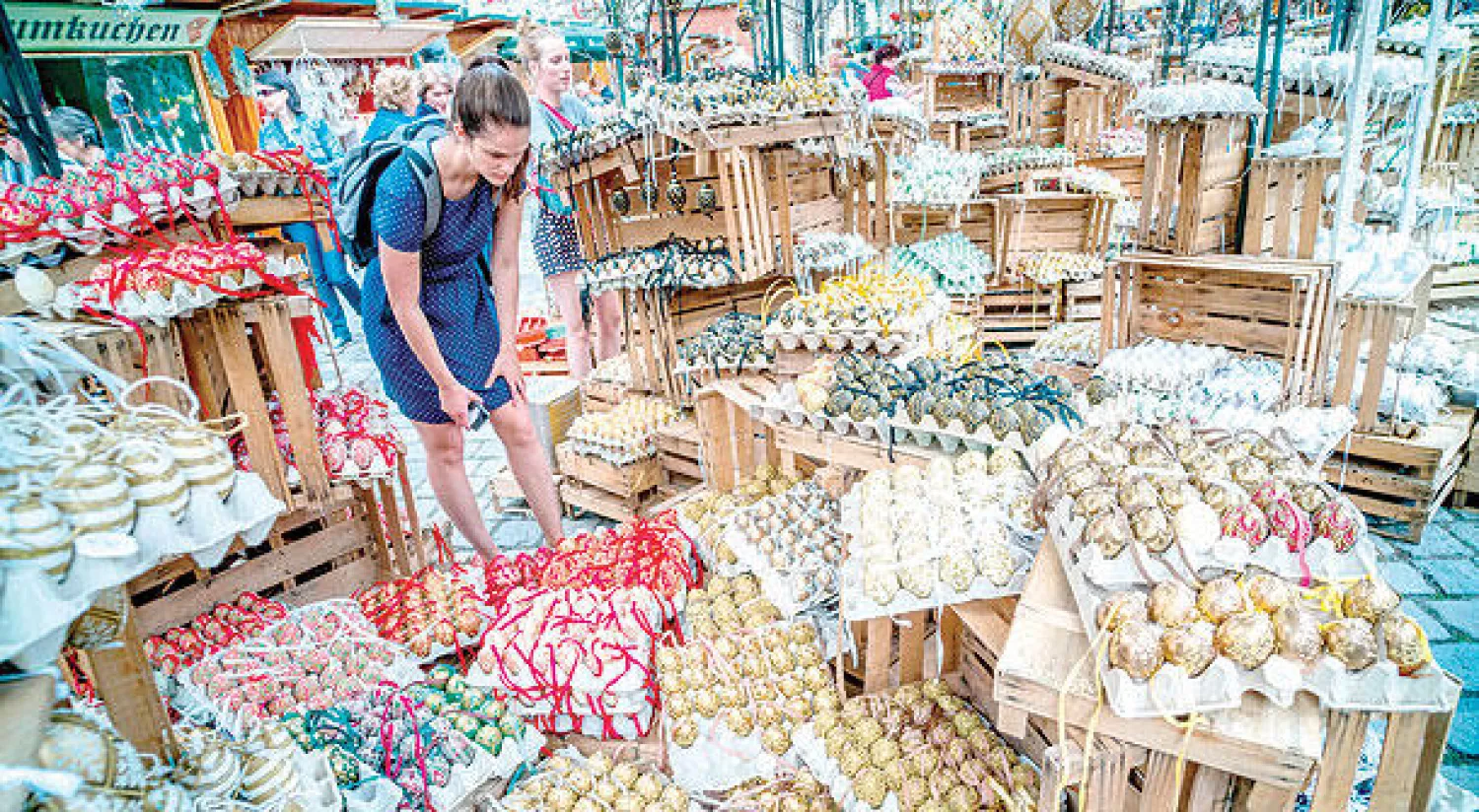 متسوقة تتفحص أطباق البيض الملون في سوق عيد الفصح بفيينا (أ.ف.ب)